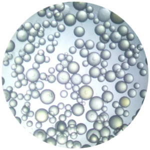 Close-up of numerous iridescent bubbles in a pale liquid, forming a dense cluster.